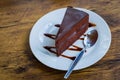 Piece of chocolate cake with spoon on white plate