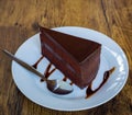 Piece of chocolate cake with spoon on white plate