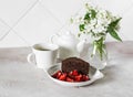 Piece of chocolate cake, strawberries and green tea on a light background. Delicious breakfast or snack