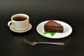 A piece of chocolate puff cheesecake on a plate with mint, a fork and a cup of hot black coffee on a black background Royalty Free Stock Photo