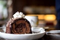 A piece of chocolate roll cake and whipped cream on the top in white ceramics plate and coffee cup on wooden table Royalty Free Stock Photo