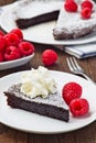 Piece of chocolate sticky brownie cake, swedish dessert Kladdkaka, on plate, garnished with icing sugar, whipping cream and