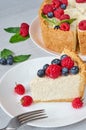 A piece of classic New York cheesecake with fresh raspberries, blueberries and mint leaves on the white plate on the gray table Royalty Free Stock Photo