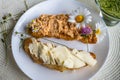 2 piece of croissant with butter and tuna spread on white plate, flowers, closeup