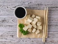 A piece of crumpled paper with soy sauce and slices of tofu cheese. Soy cheese. Flat lay. Royalty Free Stock Photo