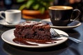 Piece of delicious brownie chocolate cake on plate and cup of coffee on table in an outdoor cafe in sunny day