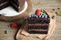 Piece of delicious chocolate cake decorated with berries on wooden table Royalty Free Stock Photo