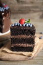 Piece of delicious chocolate cake decorated with berries on wooden table Royalty Free Stock Photo