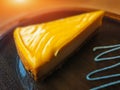 Piece of delicious cold lemon cheesecake in a wooden plate on table closeup