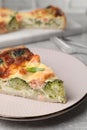 Piece of delicious homemade quiche with salmon and broccoli on light grey table, closeup Royalty Free Stock Photo