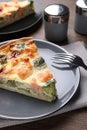 Piece of delicious homemade salmon quiche with broccoli and fork on wooden table Royalty Free Stock Photo