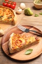 Piece of delicious homemade vegetable quiche and fork on wooden plate Royalty Free Stock Photo