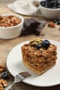 Piece of delicious layered honey cake with blueberries and nuts on wooden table, closeup Royalty Free Stock Photo