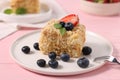 Piece of delicious Napoleon cake with fresh berries on pink table, closeup Royalty Free Stock Photo