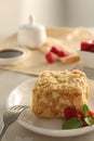 Piece of delicious Napoleon cake, raspberries and fork on beige table