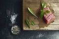 A piece of fish is on a wooden cutting board with a few herbs and spices Royalty Free Stock Photo