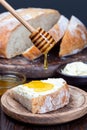 Piece of fresh backed Classic Boule bread with butter and honey on wooden plate, vertical Royalty Free Stock Photo