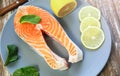 A piece of fresh salmon fish steak on a gray plate with spinach and lemon, on  a gray wooden background. Omega 3 vitamin, healthy Royalty Free Stock Photo