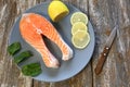 A piece of fresh salmon fish steak on a gray plate with spinach and lemon, on  a gray wooden background. Omega 3 vitamin, healthy Royalty Free Stock Photo