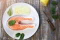 A piece of fresh salmon fish steak on a white plate with spinach and lemon, on  a gray wooden background. Omega 3 vitamin, healthy Royalty Free Stock Photo