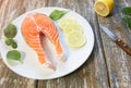 A piece of fresh salmon fish steak on a white plate with spinach and lemon, on  a gray wooden background. Omega 3 vitamin, healthy Royalty Free Stock Photo