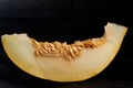 A piece of fresh sweet yellow melon sliced on wooden black table. Piece of raw organic melon on wooden dark surface close up Royalty Free Stock Photo