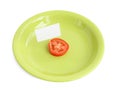 Piece of a fresh tomato with blank cardboard information tag on a green plate