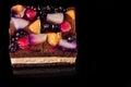 Piece of fruit cake with jelly and cream. Black background. Top view