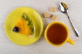 Piece of fruit pie in saucer, lumpy sugar, teaspoon, tea