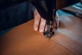 A piece of genuine leather is sewn by a tailor on a sewing machine. Neat seam