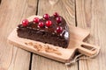 A piece of gluten-free cake in chocolate, decorated with cranberries, on the kitchen board, on a wooden background. Royalty Free Stock Photo