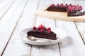 A piece of gluten-free chocolate cake decorated with cranberries, on a white plate, on a light wooden table. Royalty Free Stock Photo