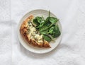 A piece of gorgonzola, pear, honey pizza and fresh spinach in a plate on a light background, top view