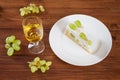 Piece of grape torte with green grapes on plate, white wine glas