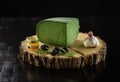 Piece of green pesto cheese, jar of jam, olives and garlic on wooden board Royalty Free Stock Photo