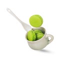 A piece of green pistachio macaroon or french macarons falling on a soft green ceramic cup