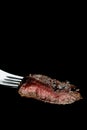 Piece of a grilled medium rare steak on a fork