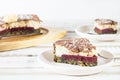 A piece of healthy cake on a saucer, without eggs and gluten, with a cream and strawberry layer, on a light wooden background