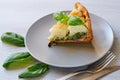 A piece of healthy cauliflower pie on the gray plate decorated with fresh basil leaves and vintage silver knife and fork