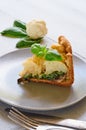 A piece of healthy cauliflower pie on the gray plate decorated with fresh basil leaves and vintage silver knife and fork Royalty Free Stock Photo