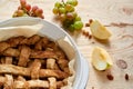 A piece of homemade american apple pie in baked form on brown wooden table with raisins and fresh fruits - apples, grapes Royalty Free Stock Photo