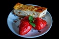 Piece of homemade cheesecake on a plate decorated with fresh strawberries and mint leaves Royalty Free Stock Photo