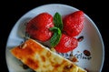 Piece of homemade cheesecake on a plate decorated with fresh strawberries and mint leaves Royalty Free Stock Photo