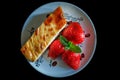 Piece of homemade cheesecake on a plate decorated with fresh strawberries and mint leaves Royalty Free Stock Photo