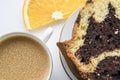 Piece of homemade chocolat-orange cake decorated with orange slice and a cup of espresso coffee on a white background