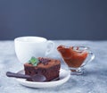 A piece of homemade chocolate cake on the plate with icing, mint leaf and chocolate spoon on the gray table Royalty Free Stock Photo