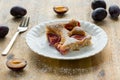 Piece of homemade plum pie on a white plate with organic plums and fork on wooden table Royalty Free Stock Photo