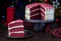 Piece of homemade red velvet cake with cream cheese frosting on metal plate, low key photo with boke lights and christmas Royalty Free Stock Photo