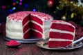Piece of homemade red velvet cake with cream cheese frosting and red sugar decoration, low key photo with boke lights and Royalty Free Stock Photo