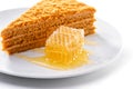 Piece of honeycomb close-up next to piece of honey cream cake on white background